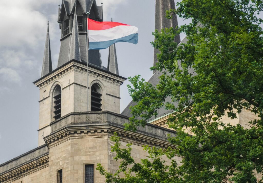 A captivating view of a church in Luxembourg with the national flag and lush greenery.