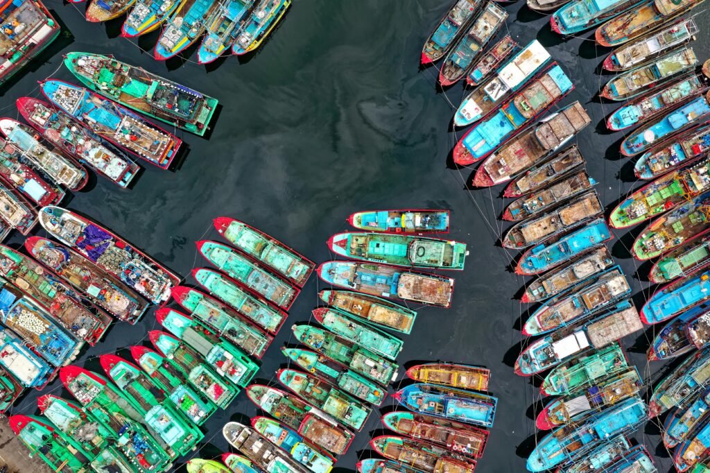 Aerial shot of colorful fishing boats docked in Penjaringan, Jakarta, Indonesia, showcasing maritime culture.