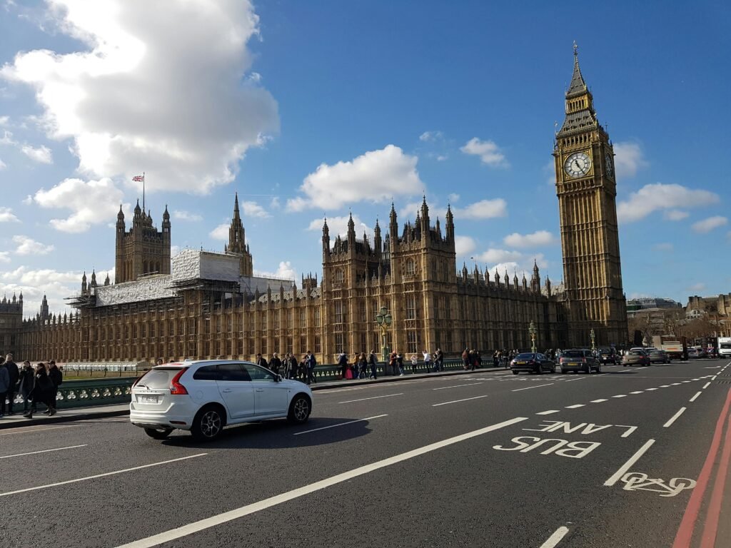 View of Big Ben and the Palace of Westminster with traffic and pedestrians on a sunny day in London.