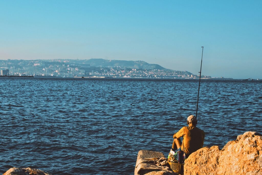 A lone fisherman enjoys a quiet day by the sea in Hussein Dey, Algeria.